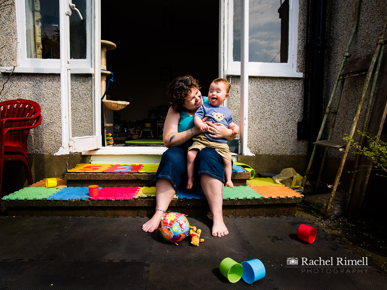 mother and son with downs syndrome sit on back step documentary portrait