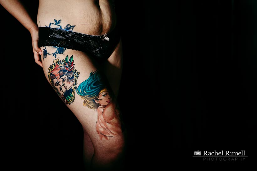 Motherhood and Identity photo of woman's legs with colourful tattoos against a black background