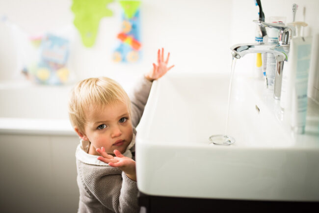 candid portrait of a young girl at the bathroom sink. Alternative family photography London
