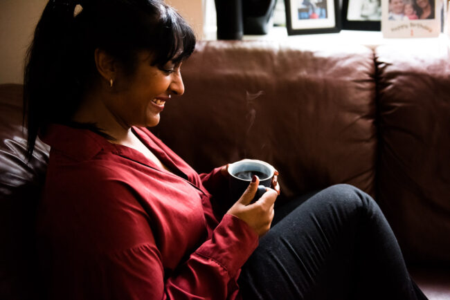 informal headshot portrait of entrepreneur on sofa with cup of coffee, east London