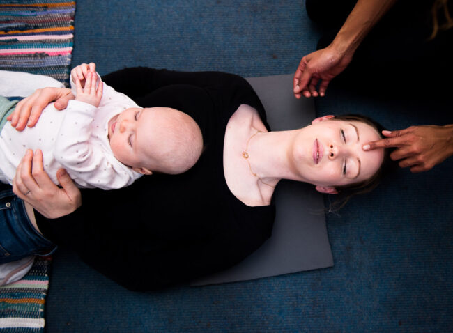 Mother and baby at a baby massage class in South London with mother receiving a head massage