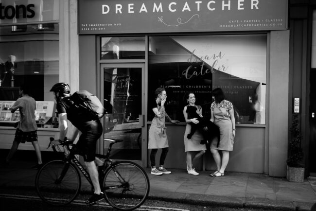 Informal environmental portrait of cafe owners at Dreamcatcher outside their cafe with bicycle going past