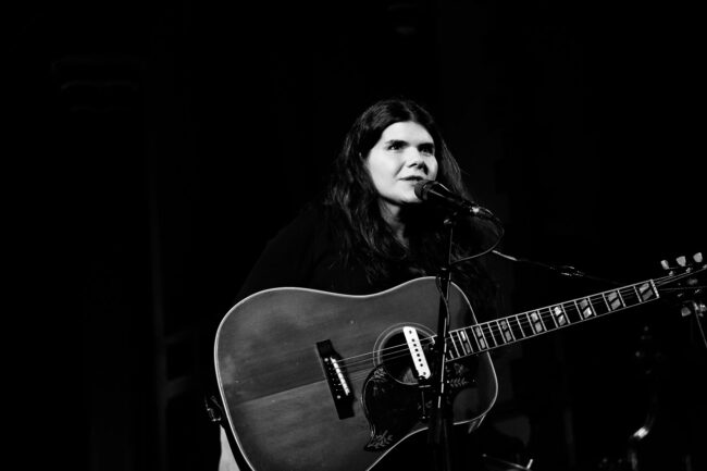 Blacka nd white image of Michele Stodart at Sydenham Arts event on stage with guitar editorial photo