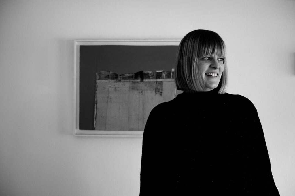 Natural light relaxed professional headshot of life coach Janine Green in black dress with painting in background, Crystal Palace, London