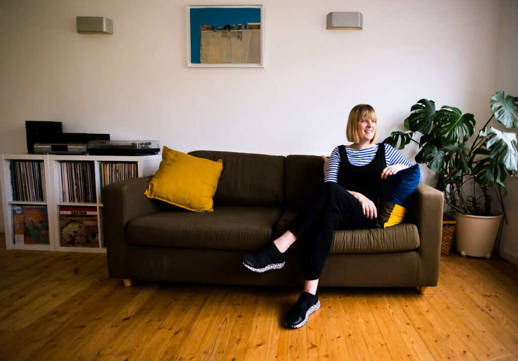 relaxed personal branding portrait of Janine Green Coaching on her sofa in her home with records and cheesplant in background, Crystal Palace, London