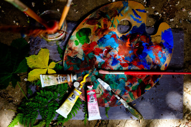 flat lay of oil paints with brushes and palette with rustic leaves in background, London