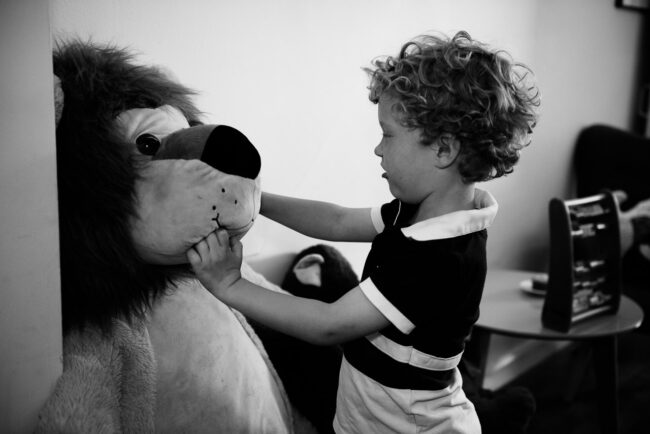black and white image of a boy playing with a giant teddy lion in Crystal Palace