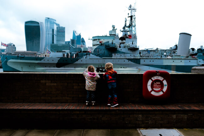 two children looking at HMS Belfast, one wearing a Spiderman outfit, on a London vacation photography session
