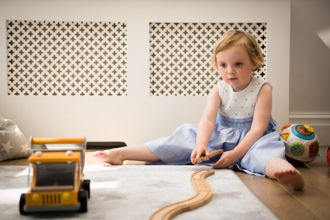 Natural portrait of girl in lilac dress playing with trains at her home in Tooting, UK family photography