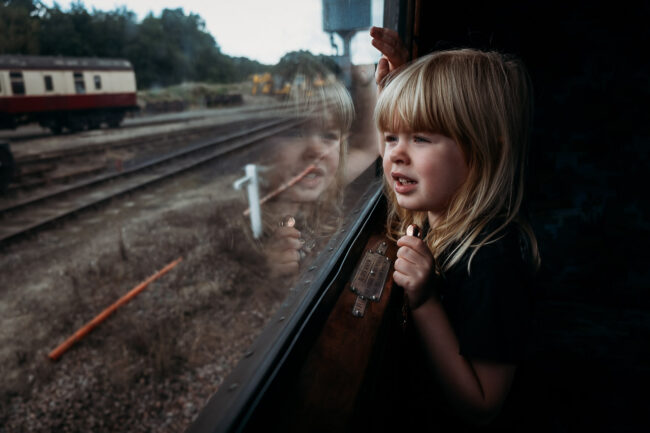 blonde girl looking out of steam train window on holiday in UK