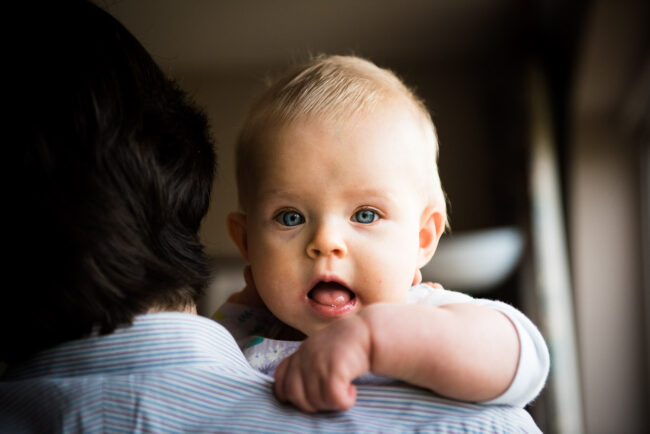 candid family photography image of baby girl looking over daddy's shoulder in natural light, Orpington, Bromley