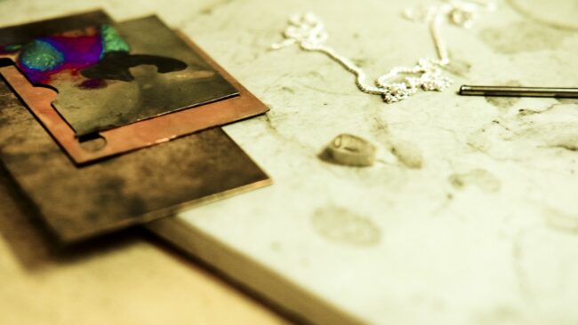 detail image of gold and bronze and a silver chain on jeweller's workspace in Crystal Palace studio