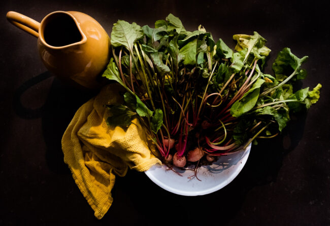 overhead shot of beetroots in a white bowl with yellow jug and table linen