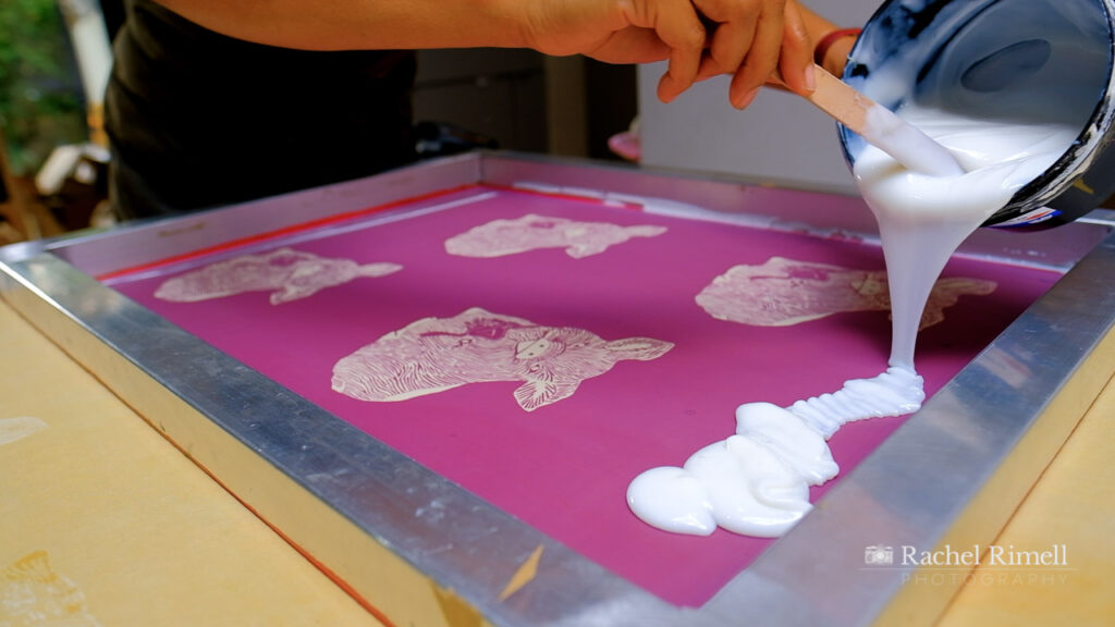 detail of textile artist pouring print liquid onto screen print