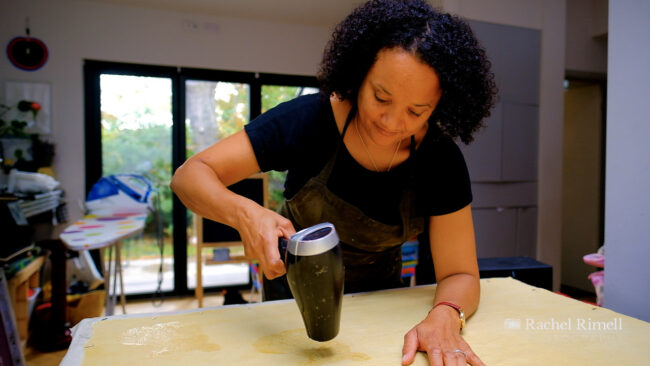 environmental portrai of textile artist Emma Walker drying her screen printed design on a piece of fabric
