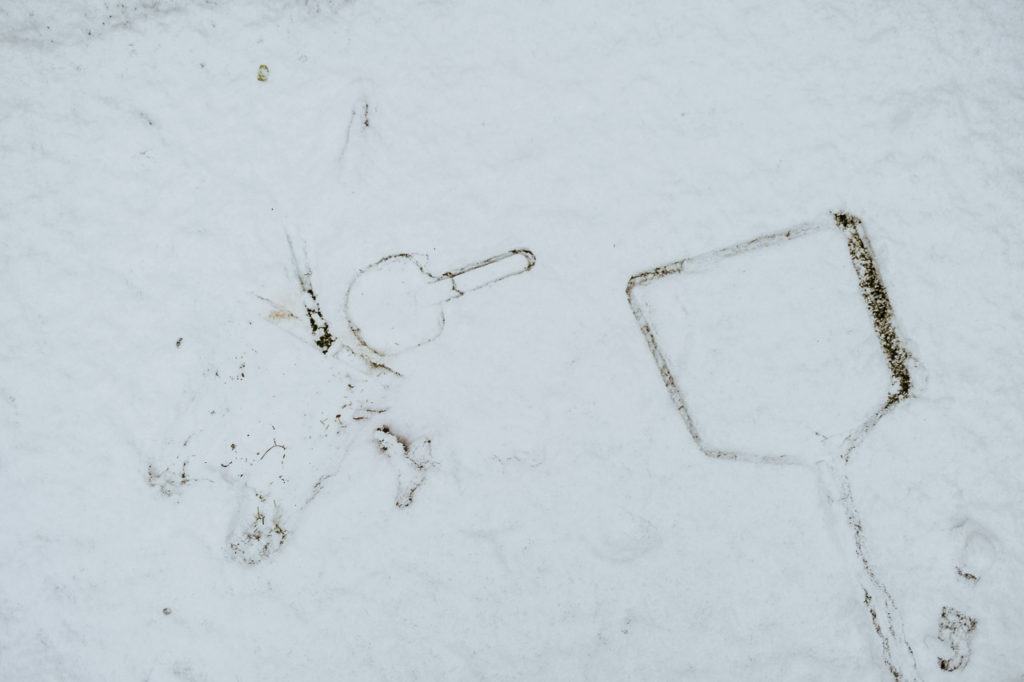 the imprint of a child's seaside bucket and spade and a fishing net in the snow