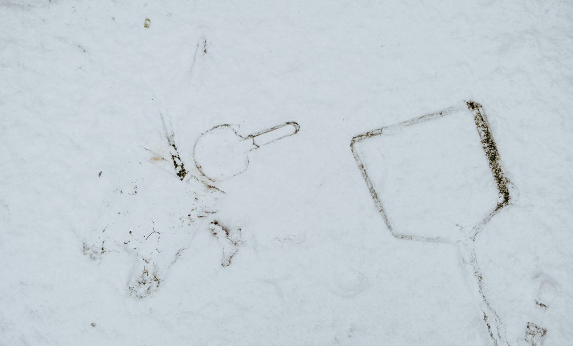 the imprint of a child's seaside bucket and spade and a fishing net in the snow