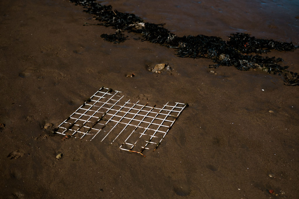 white metal grate lying on the sand on the strandline at Whitby harbour