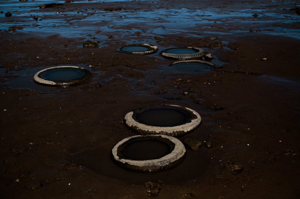 old tyres buried in the sand on the strandline at Whitby harbour