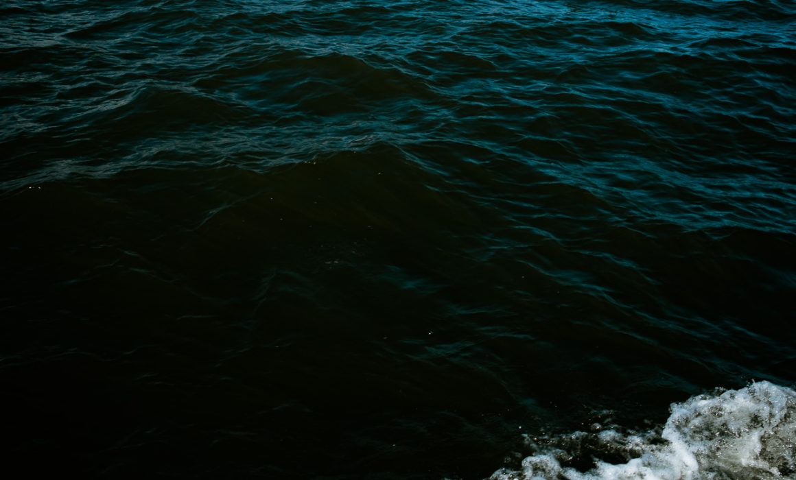 Image of the sea with corner of white foam and green blue water