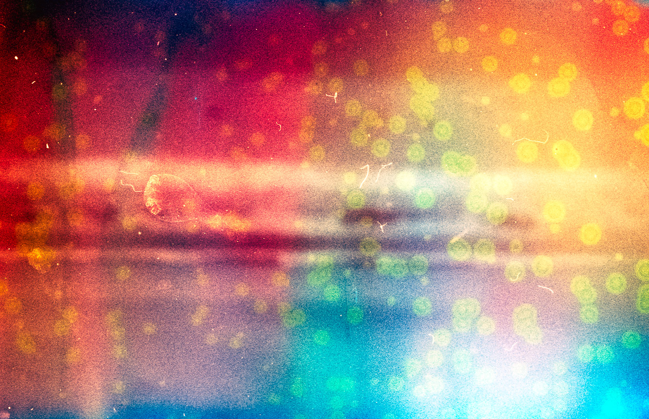 Vestige #1 – North Yorkshire photographic artist semi abstract image of waves in the background with reds and blues with yellow spots caused by immersing the 35mm film in seawater before developing so that salt crystallises on the final negative. Taken at Hunmanby Gap, North Yorkshire.