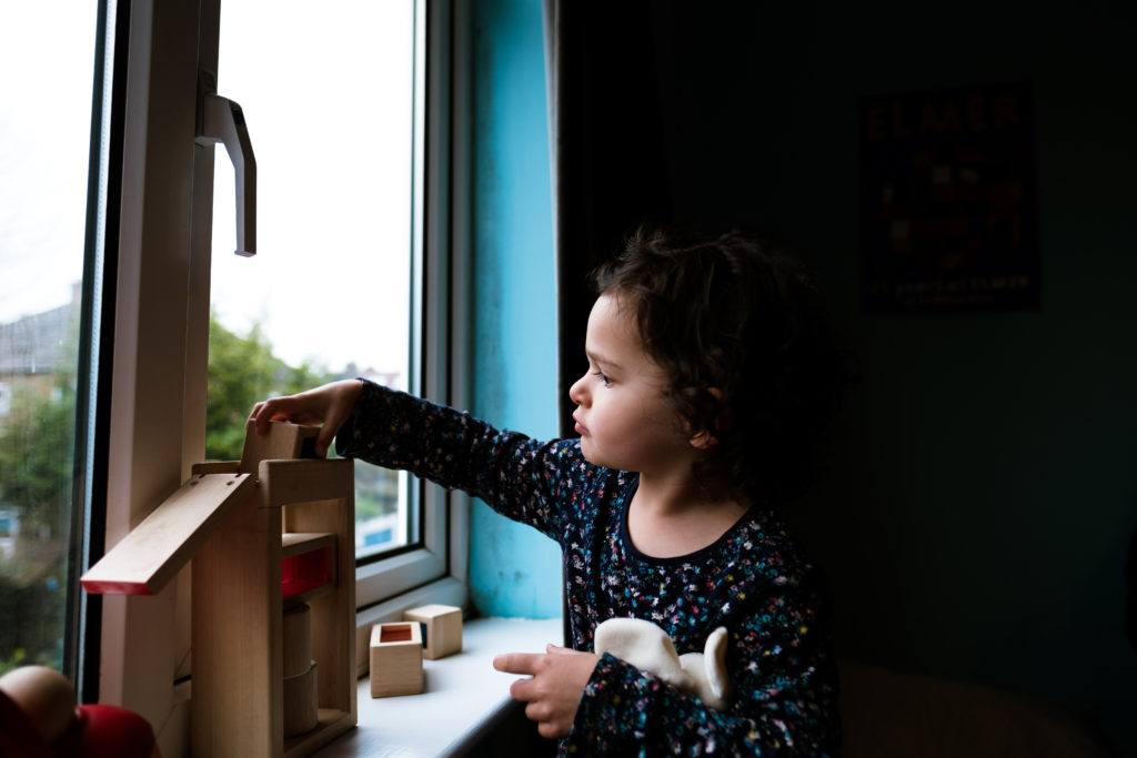 candid portrait of a young girl playing with a puzzle toy with window light on her face North Yorkshire