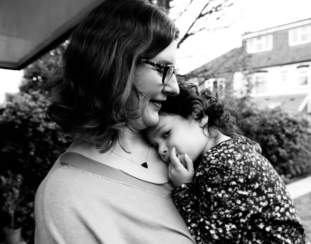 mother holding her young daughter who is sucking her thumb natural family portrait Yorkshire