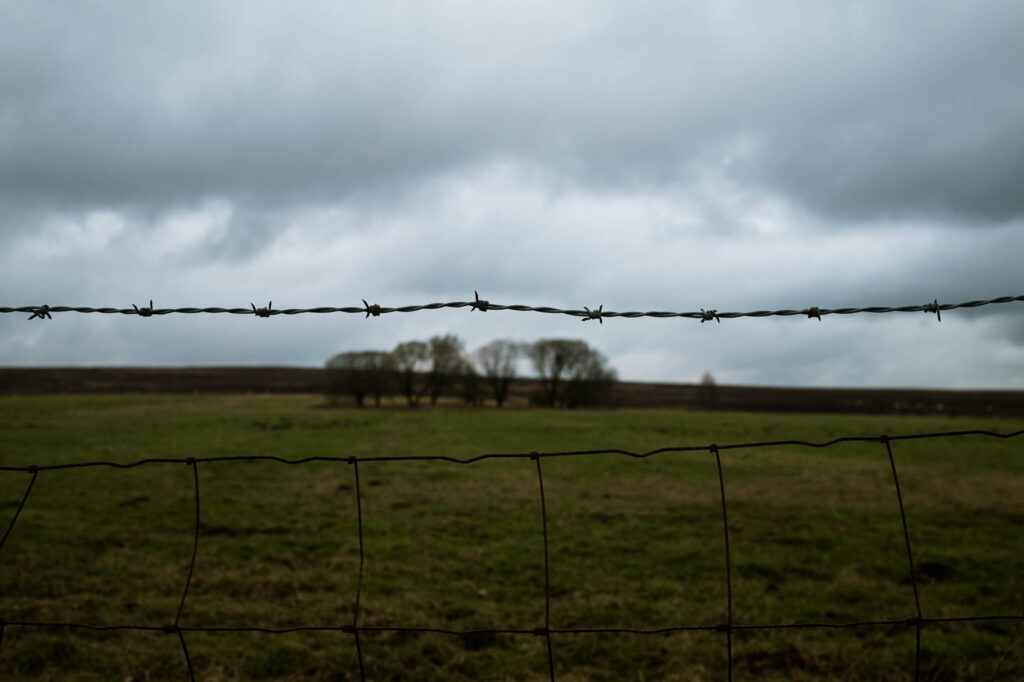 Photographic work exploring trespass and right to roam North Yorkshire. Image of trees in distance with barbed wire in forefront