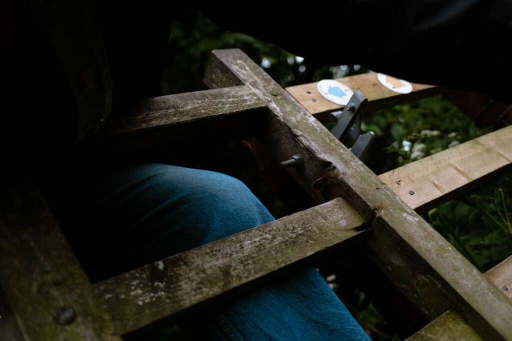 Photographic work exploring trespass and right to roam North Yorkshire. Image of a knee in blue jeans crossing a fence