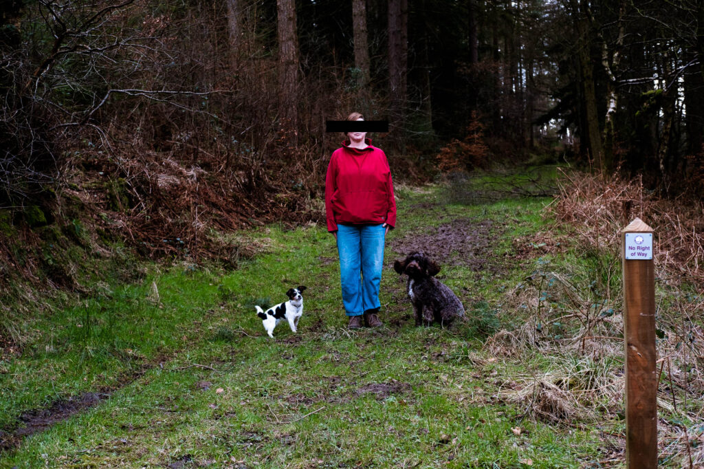 Photographic work exploring trespass and right to roam North Yorkshire, Woman in blue jeans and red top with eyes blacked out and two dogs