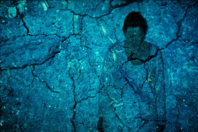 Photographic work exploring trespass and right to roam North Yorkshire. discoloured in blue cracked earth projected onto a woman in white