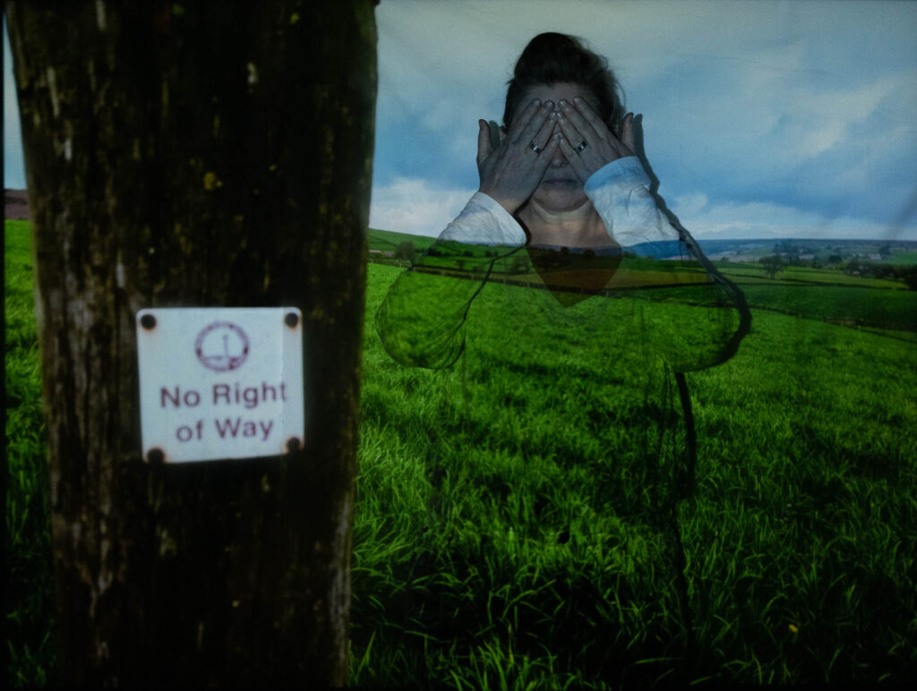 Photographic work exploring trespass and right to roam North Yorkshire. Woman with hands over her eyes with a projected image of the landscape and no right of way sign