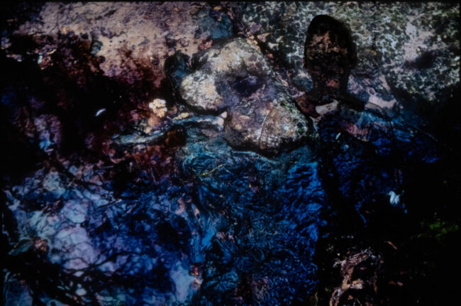 Photographic work exploring trespass and right to roam North Yorkshire. woman standing against a projected image of stones and water