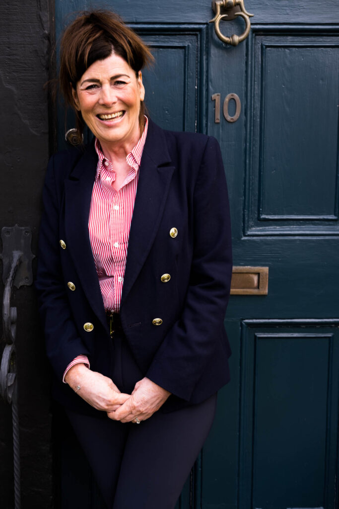 white woman with pink shirt and blue bazer against a blue door